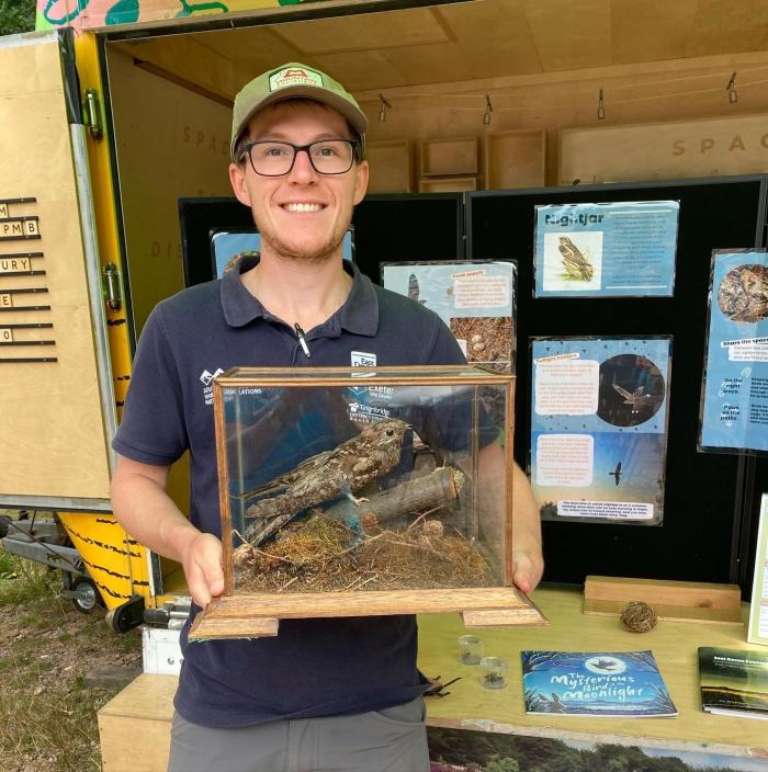 A photo of Wildlife Warden Caius holding a taxidermy Nightjar