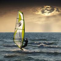 Someone windsurfing with god rays behind