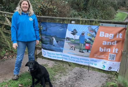 A photo of Julie with dog Maisie in front of one of the campaign banners